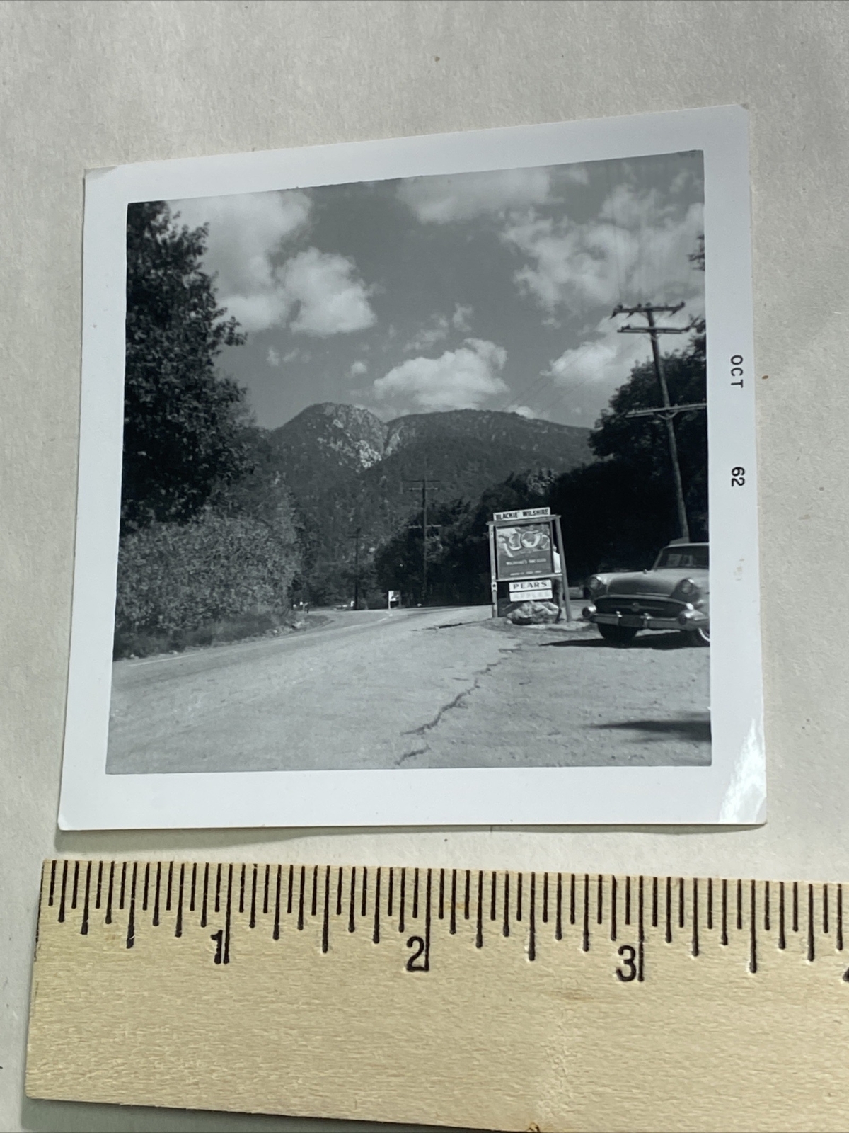 B&W Photo of an ad sign that says, « Blackie Wilshire, Pears and Apples », 1962